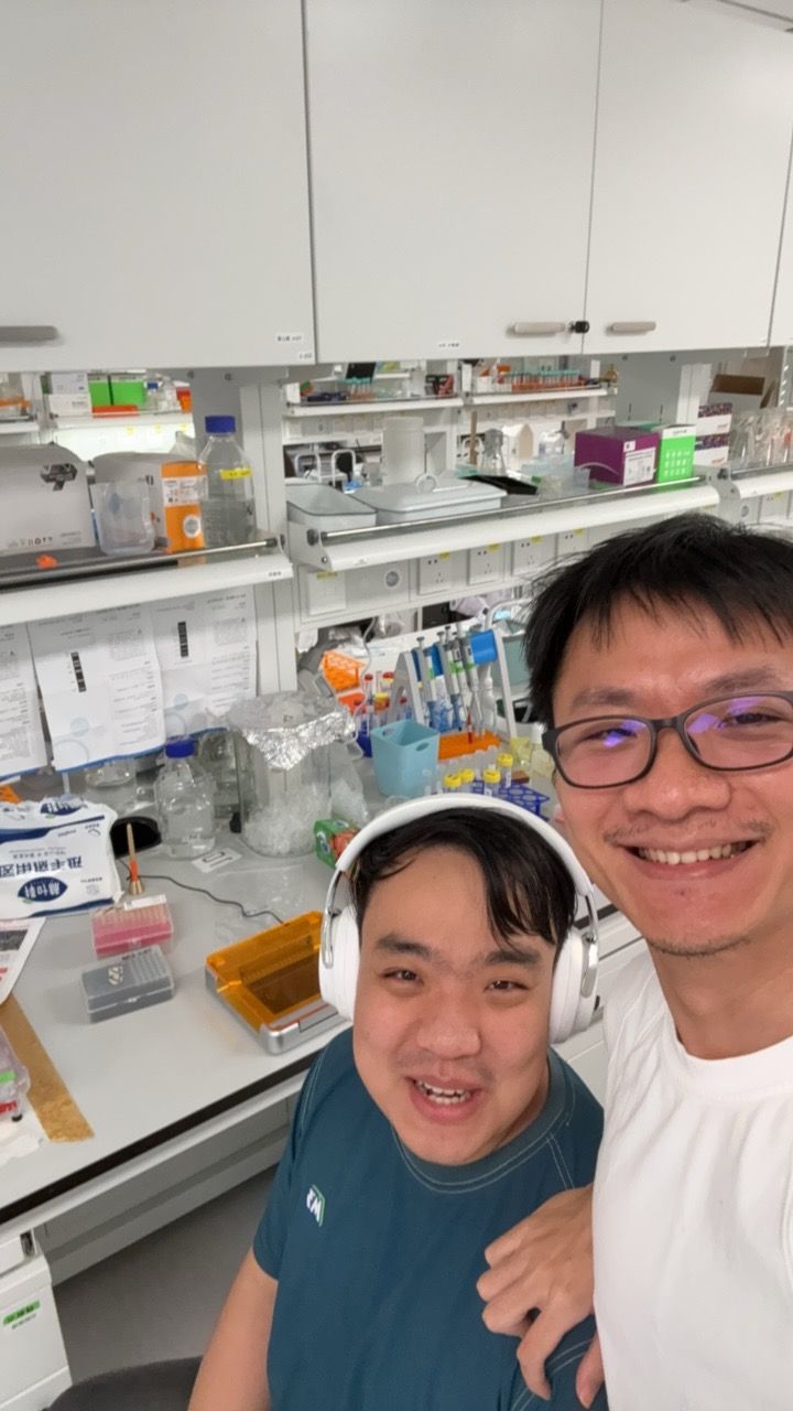 Two lab members at the bench, one wearing headphones