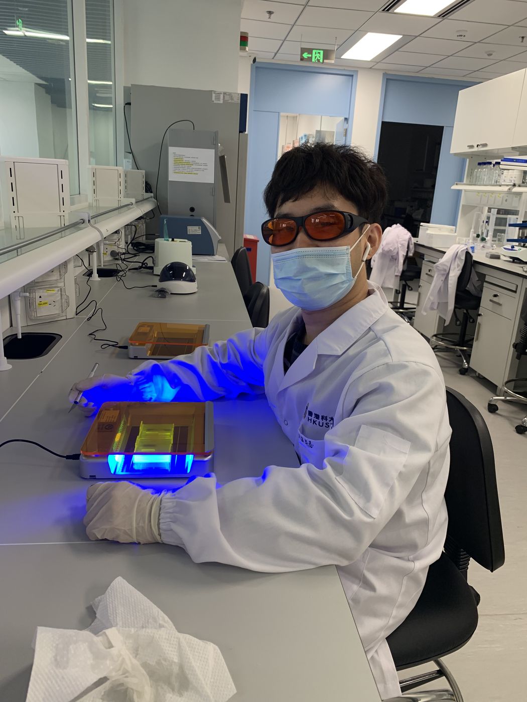 Lab member in goggles working at a blue-light gel illuminator