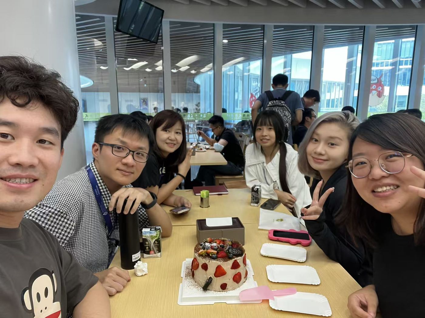 Lab members with a cake at a table in the campus canteen
