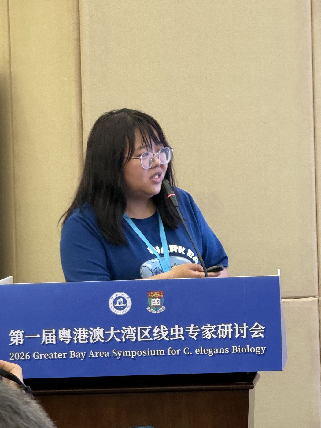 Lab member speaking at the podium of the 2026 Greater Bay Area Symposium for C. elegans Biology